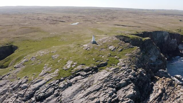 Point-of-interest drone shot of a cliffside lighthouse with peat banks and moorland in the background. Filmed on the moorland near Ness on the Isle of Lewis, part of the Outer Hebrides of Scotland.