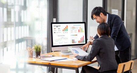 Team of confident Asian business people point to graphs and charts to analyze market data, balance sheet, account, net profit to plan new sales strategies to increase production capacity.