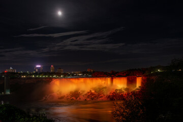 Niagara Falls lit up in gold and yellow under the moonlight. Ontario, Canada.