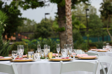 Table set up for outdoor wedding reception in white, pink and gold.