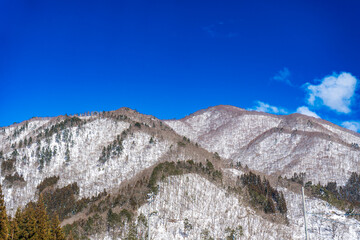 Fototapeta na wymiar 冬の白川郷の青空と雪の積もった山々