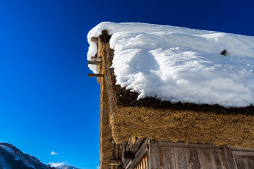 雪の積もった茅葺き屋根 - obrazy, fototapety, plakaty