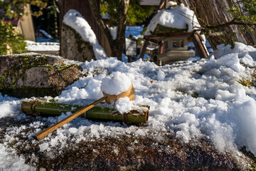 雪の積もった手水舎の柄杓