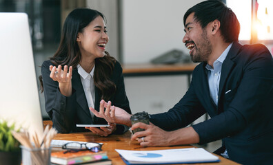 Two young business colleagues talking and discussing on project together with happiness at office.