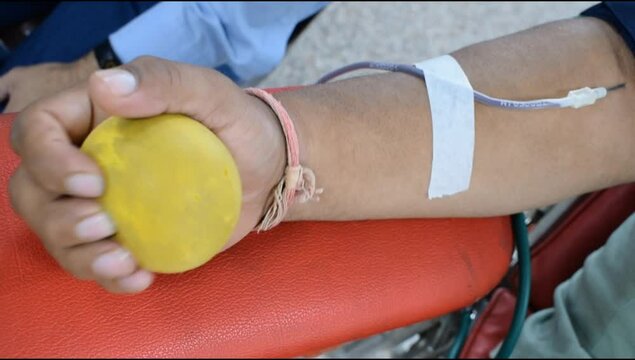 Blood donor at Blood donation camp held with a bouncy ball holding in hand at Balaji Temple, Vivek Vihar, Delhi, India, Image for World blood donor day on June 14 every year, Blood Donation Camp