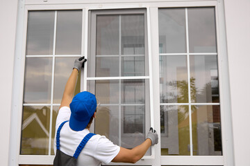 View from back master in working uniform of blue color, in his hands high raises mosquito net for...