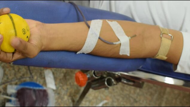 Blood donor at Blood donation camp held with a bouncy ball holding in hand at Balaji Temple, Vivek Vihar, Delhi, India, Image for World blood donor day on June 14 every year, Blood Donation Camp