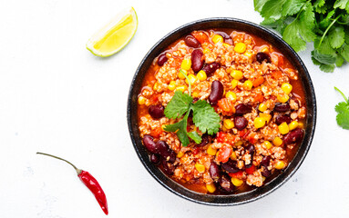 Chili con carne with beef, red beans, paprika, corn and hot peppers in tomato sauce, spicy tex-mex dish, white table background, top view