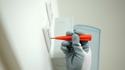 Close up electric screwdriver of electrician man in uniform maintenance or fixing switches socket circuit breaker ,electrical system. Technician fixing an electric fuse at home. Home service concept.