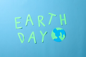 Earth day lettering and globe made from paper isolated on blue background. World earth day concept. 