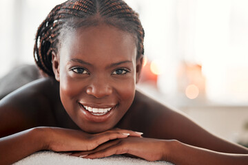Spa, portrait and black woman with smile, massage and salon luxury treatment, bare and lying on...
