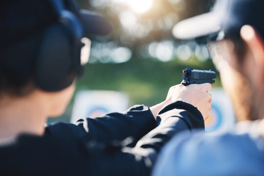 Man, woman and gun training with target, outdoor challenge and aim at police, army or security academy. Shooting coach, pistol or firearm for sport, safety and combat exercise in nature with vision
