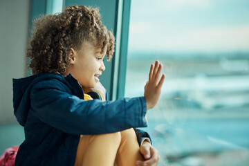 Girl child, wave and airport window for greeting, goodbye and smile for airplane, international...