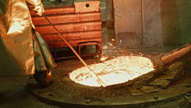 Iron foundry worker mixes molten metal