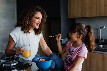 Hispanic mother and daughter eating breakfast at kitchen in Mexico Latin America