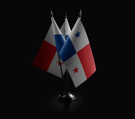 Small national flags of the Panama on a black background