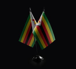 Small national flags of the Zimbabwe on a black background