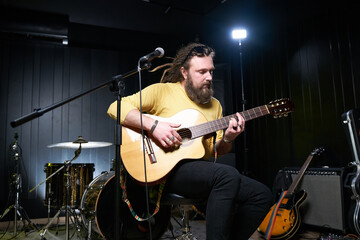 Guitarist man plays an acoustic guitar Close-up at studio