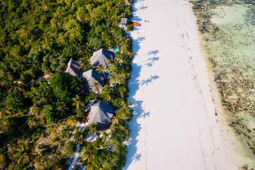 This aerial photo of Kiwengwa Beach in Zanzibar showcases the stunning natural beauty of the island, with its golden sand, turquoise waters, and lush foliage creating the perfect backdrop for a relaxi