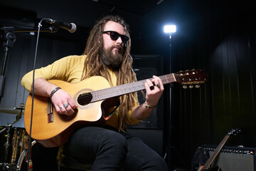 Guitarist man plays an acoustic guitar Close-up at studio