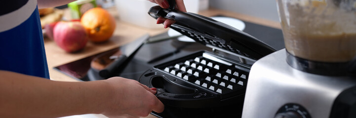 Person opens electric waffle iron in kitchen