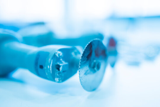 Blue tone color selective focus of medical saw with blur background.Focus on saw blade.Doctor use saw for cutting plaster cast or plastic cast in orthopedic unit inside hospital.Bone saw by surgeon.
