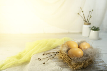 Three orange eggs lie in a nest on a table, on wooden boards. Easter card for the holiday. High...