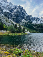 Morskie Oko lake Snowy Mountain Hut in Polish Tatry mountains, Zakopane, Poland. Beautiful green hills and mountains in dark clouds and reflection on the lake Morskie Oko lake