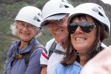 Happy senior friends hikers with backpacks and helmets enjoying trekking day on the top of mountain - Smiling climbing tourists, Freedom, sport healthy lifestyle concept