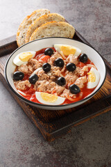 Murcian salad or mojete, a traditional fresh and light recipe that is prepared with tomato, canned tuna, black olive, egg and onion closeup on the plate on the wooden board. Vertical
