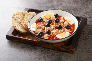 Fresh and delicious Murcian moje traditional salad with canned tomatoes, tuna, eggs and onions topped with virgin olive oil closeup on the plate on the wooden board. Horizontal