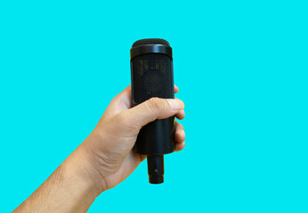 and holding condenser microphone on blue color background, top view with blank space for text