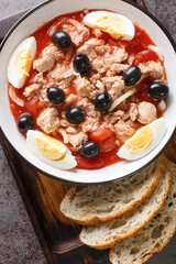 Murcian salad or mojete, a traditional fresh and light recipe that is prepared with tomato, canned tuna, black olive, egg and onion closeup on the plate. Vertical top view from above