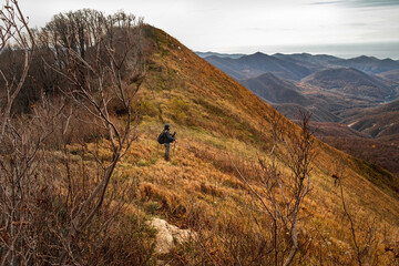 A tourist in the mountains. A young man on top of a mountain enjoying nature. A young man with a backpack descends from the top of the mountain. A man going hiking in the Caucasus mountains.