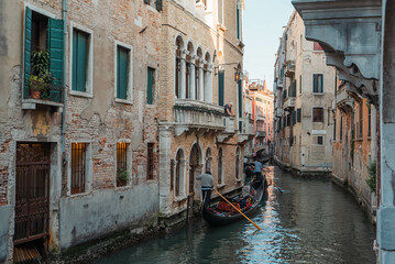 Venice Canal is lined on either side by Romanesque, Gothic, and Renaissance buildings with...