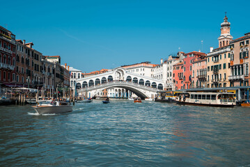 Fototapeta na wymiar The Grand Canal and Rialto Bridge are lined on either side by Venetian Buildings with local water transport in Venice, Italy.