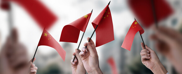 A group of people holding small flags of the China in their hands - obrazy, fototapety, plakaty