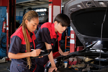 Two professional automotive mechanical partners check and repair an EV car battery and hybrid engine at a maintenance garage, expert electric vehicle service, and fixing occupations auto industry.