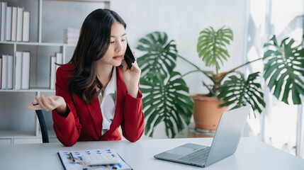 Confident Asian woman with a smile standing holding notepad, tablet and tablet at the modern home office.