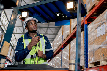 Young African forklift driver sitting in vehicle in warehouse smiling looking at camera. Safety first working for Employee concept.