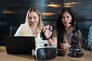 Male and female engineer working with AI robot arm system project in workshop. Male engineer using...