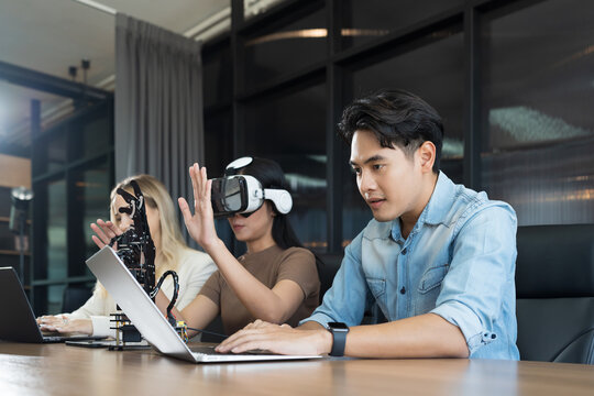 Male and female engineer working with vr glasses control AI robot arm system in workshop. Male engineer using laptop computer for control Programmable logic controller robotics arm system project