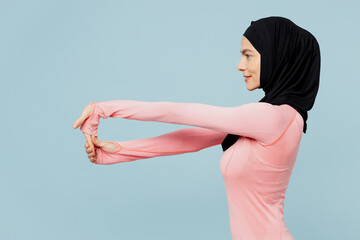 Side view young muslim fitness trainer sporty woman wears pink abaya hijab spend time in home gym...