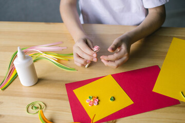 With the hands of a child, make a card out of quilling, twist a strip of pink paper with an awl