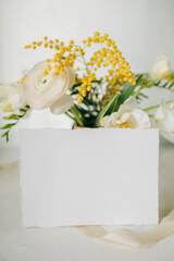 Obraz na płótnie Canvas white paper mockup with texture on festive peach background with flowers white and yellow colors,wedding invitation mockup, top view, spring mockup