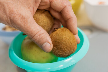 Closeup photo of man cooking summer salad with kiwi at home