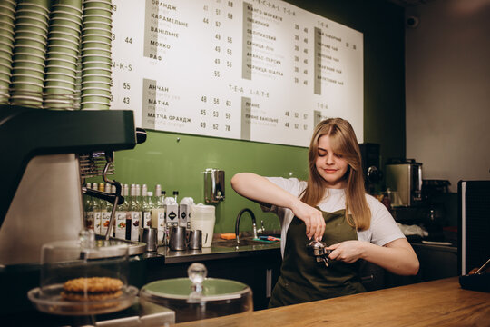 smiling barista woman standing with coffee holder full of ground coffee in her hands , barist work routine.