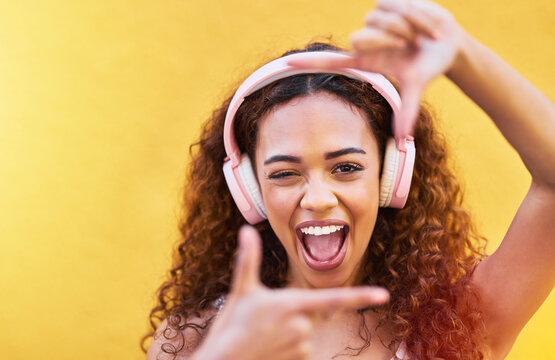 Hands, frame and portrait of woman with headphones on yellow background for profile picture. Face, female and finger framing with music for perspective, selfie and vision of happiness, smile and tech