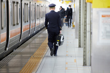 朝の名古屋駅のホームで歩く駅係員の後ろ姿