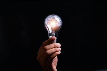 businessman Hand holding light bulb with brain glowing with orange light line and ray. Creative and...